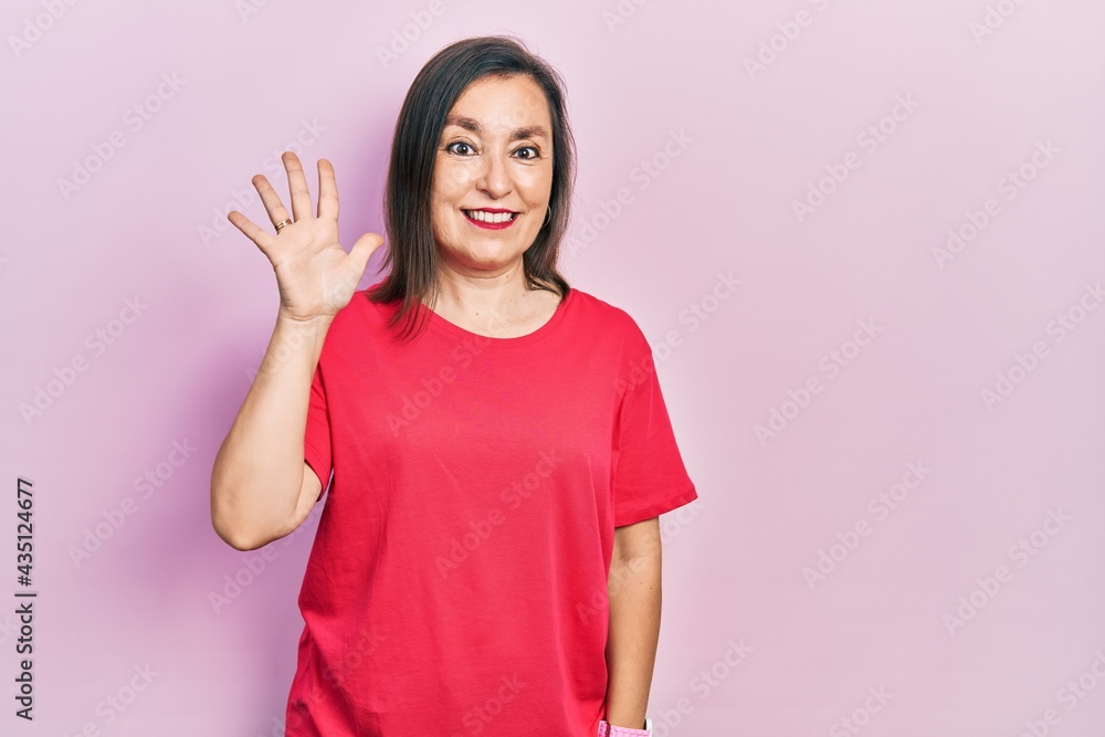 Middle age hispanic woman wearing casual clothes showing and pointing up with fingers number five while smiling confident and happy. Middle age hispanic woman wearing casual clothes showing and pointing up with fingers number five while smiling confident and happy.