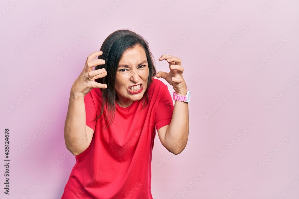 Middle age hispanic woman wearing casual clothes shouting frustrated with rage, hands trying to strangle, yelling mad Middle age hispanic woman wearing casual clothes shouting frustrated with rage, hands trying to strangle, yelling mad