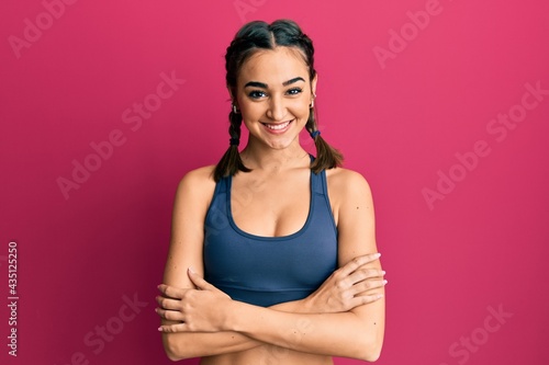 Young brunette girl wearing sportswear and braids happy face smiling with crossed arms looking at the camera. positive person.
