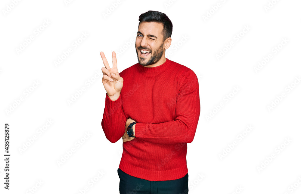 Young hispanic man wearing casual clothes smiling with happy face winking at the camera doing victory sign with fingers. number two. Young hispanic man wearing casual clothes smiling with happy face winking at the camera doing victory sign with fingers. number two.