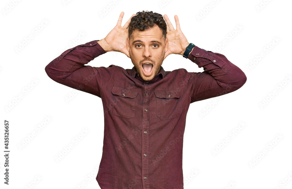 Young hispanic man wearing casual clothes smiling cheerful playing peek a boo with hands showing face. surprised and exited Young hispanic man wearing casual clothes smiling cheerful playing peek a boo with hands showing face. surprised and exited