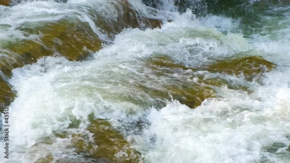 Mountain river with clear turquoise water falling down in cascades between wet boulders with thick white foam. Mountain river with clear turquoise water falling down in cascades between wet boulders with thick white foam.