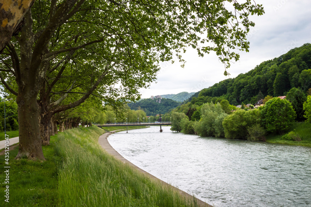 View at the Savinja river with Old Castle on a hill in the background in Celje under overcast sky in changeable weather. Celje is the third-largest town in Slovenia. View at the Savinja river with Old Castle on a hill in the background in Celje under overcast sky in changeable weather. Celje is the third-largest town in Slovenia.