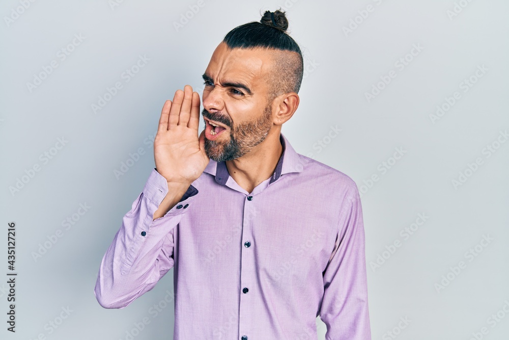 Young hispanic man wearing casual clothes shouting and screaming loud to side with hand on mouth. communication concept. Young hispanic man wearing casual clothes shouting and screaming loud to side with hand on mouth. communication concept.