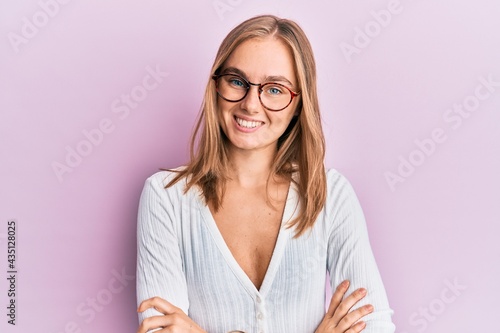 Beautiful blonde woman wearing casual clothes and glasses happy face smiling with crossed arms looking at the camera. positive person.