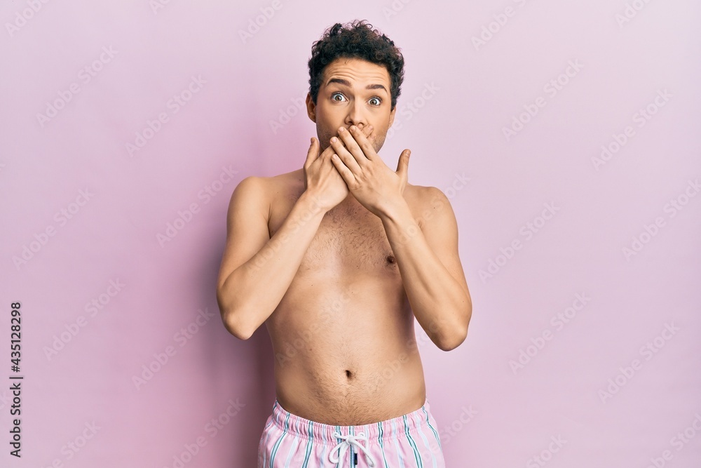 Young handsome man wearing swimwear shirtless shocked covering mouth with hands for mistake. secret concept.