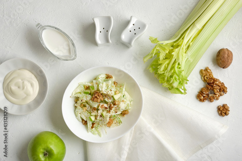 Waldorf salad with celery, apples and walnuts on a light background