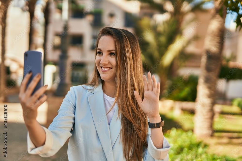Young blonde businesswoman making video call using smartphone at the city. Young blonde businesswoman making video call using smartphone at the city.