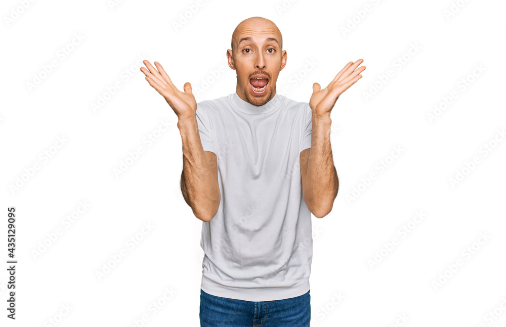 Bald man with beard wearing casual white t shirt celebrating crazy and amazed for success with arms raised and open eyes screaming excited. winner concept Bald man with beard wearing casual white t shirt celebrating crazy and amazed for success with arms raised and open eyes screaming excited. winner concept