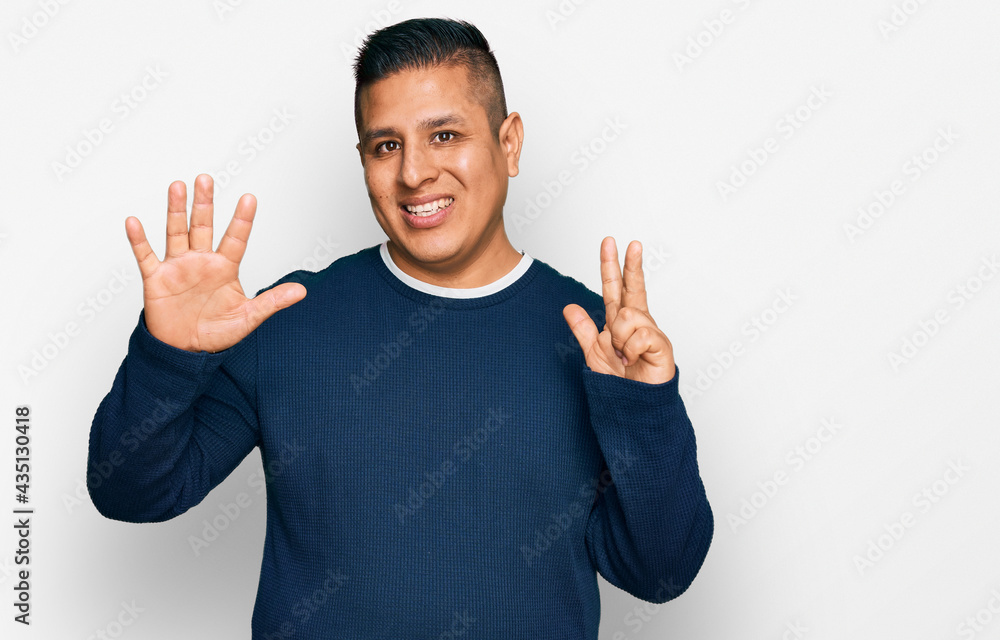 Fototapeta premium Young latin man wearing casual clothes showing and pointing up with fingers number eight while smiling confident and happy.