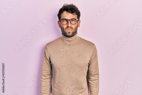 Handsome man with beard wearing turtleneck sweater and glasses skeptic and nervous, frowning upset because of problem. negative person.