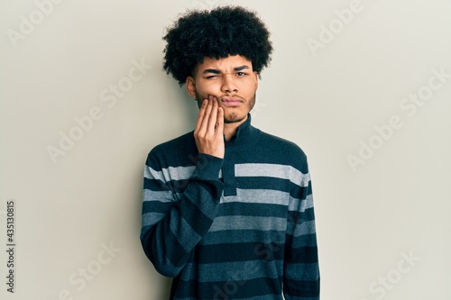 Young african american man with afro hair wearing casual clothes touching mouth with hand with painful expression because of toothache or dental illness on teeth. dentist