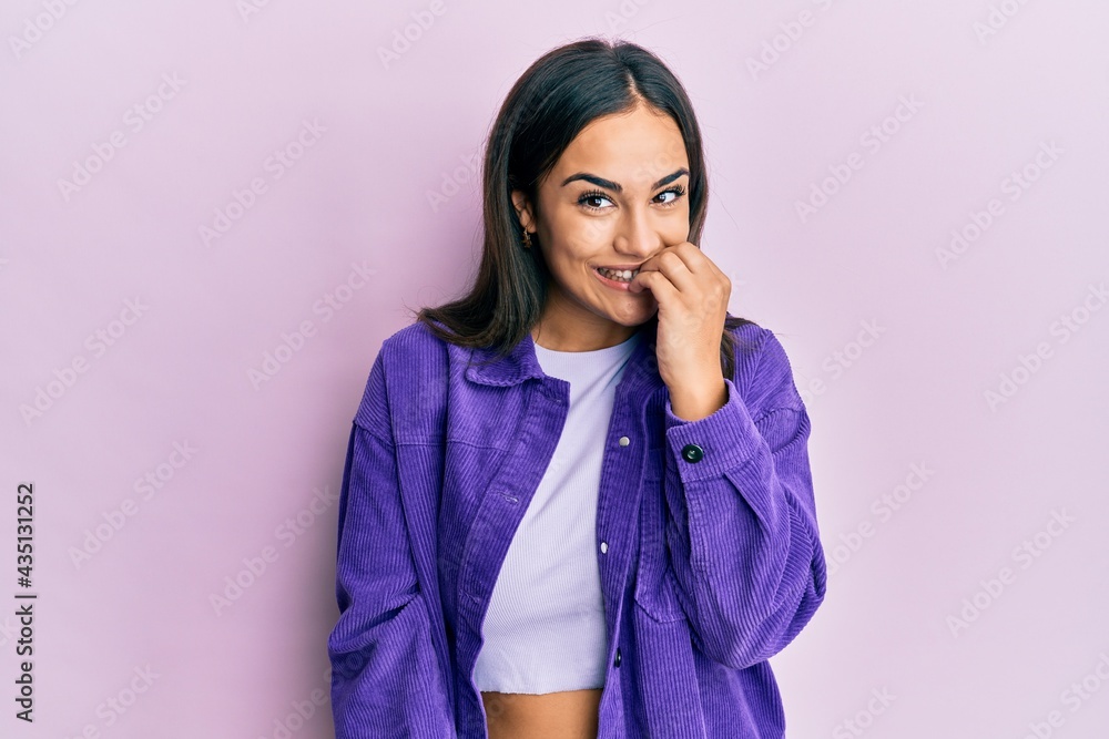Young brunette woman wearing casual clothes looking stressed and nervous with hands on mouth biting nails. anxiety problem. Young brunette woman wearing casual clothes looking stressed and nervous with hands on mouth biting nails. anxiety problem.
