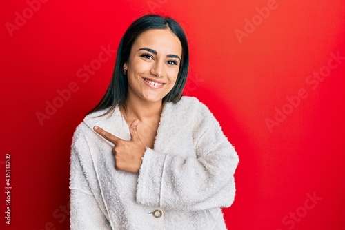 Young brunette woman wearing casual clothes smiling cheerful pointing with hand and finger up to the side © Krakenimages.com