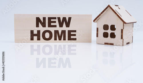 There is a wooden house and a sign on the table - NEW HOME