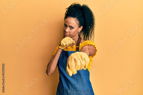Middle age african american woman wearing professional apron punching fist to fight  aggressive and angry attack  threat and violence