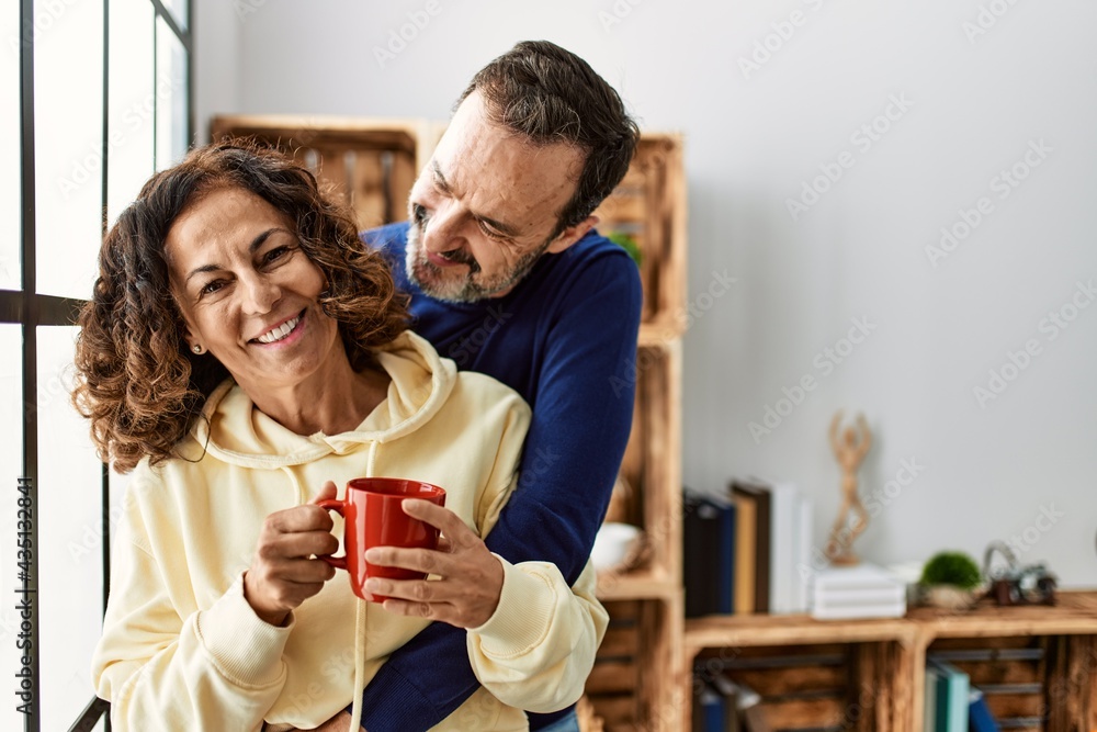 Middle age hispanic couple smiling happy and drinking coffee. Leaning on the window at home. Middle age hispanic couple smiling happy and drinking coffee. Leaning on the window at home.