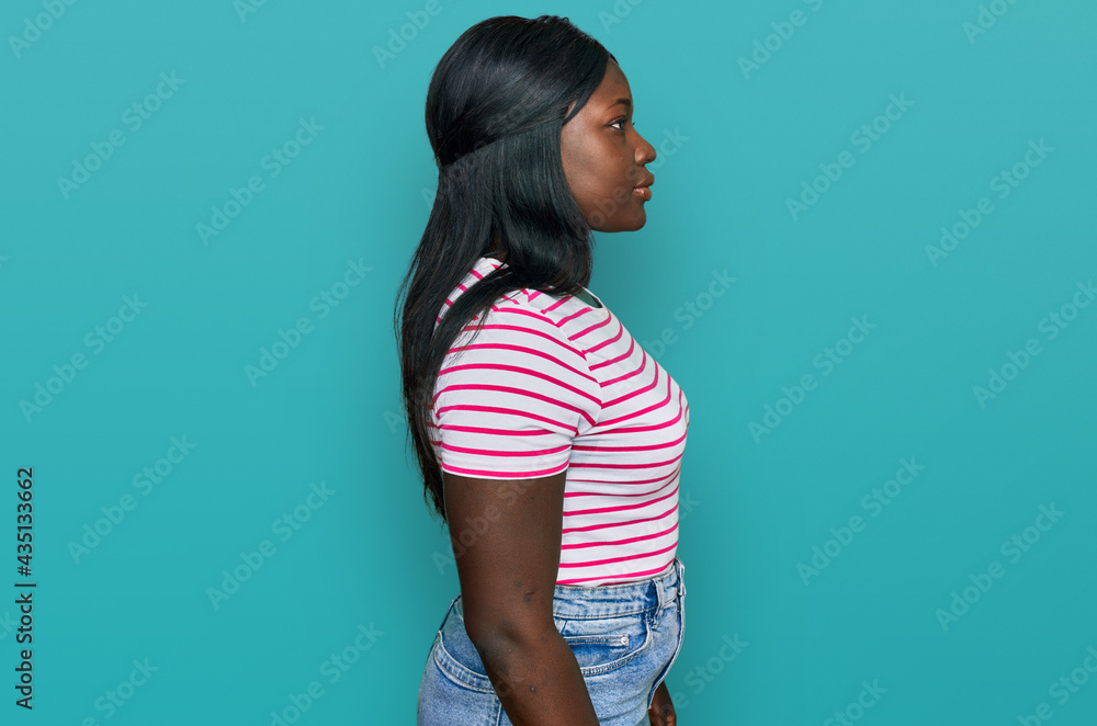African young woman wearing casual striped t shirt looking to side, relax profile pose with natural face with confident smile. African young woman wearing casual striped t shirt looking to side, relax profile pose with natural face with confident smile.