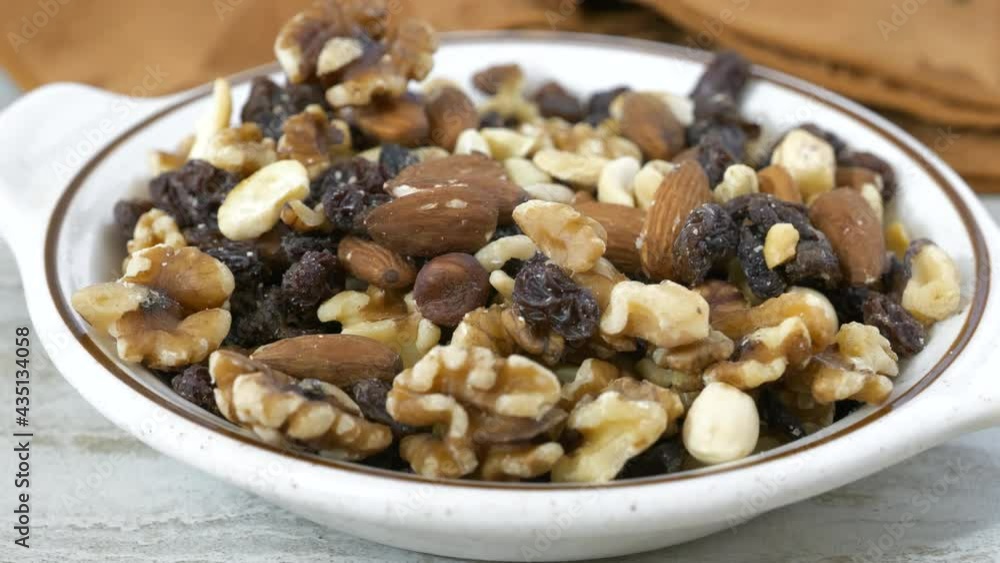 Eating a handful of healthy gourmet trail mix with nuts and raisins close up Eating a handful of healthy gourmet trail mix with nuts and raisins close up