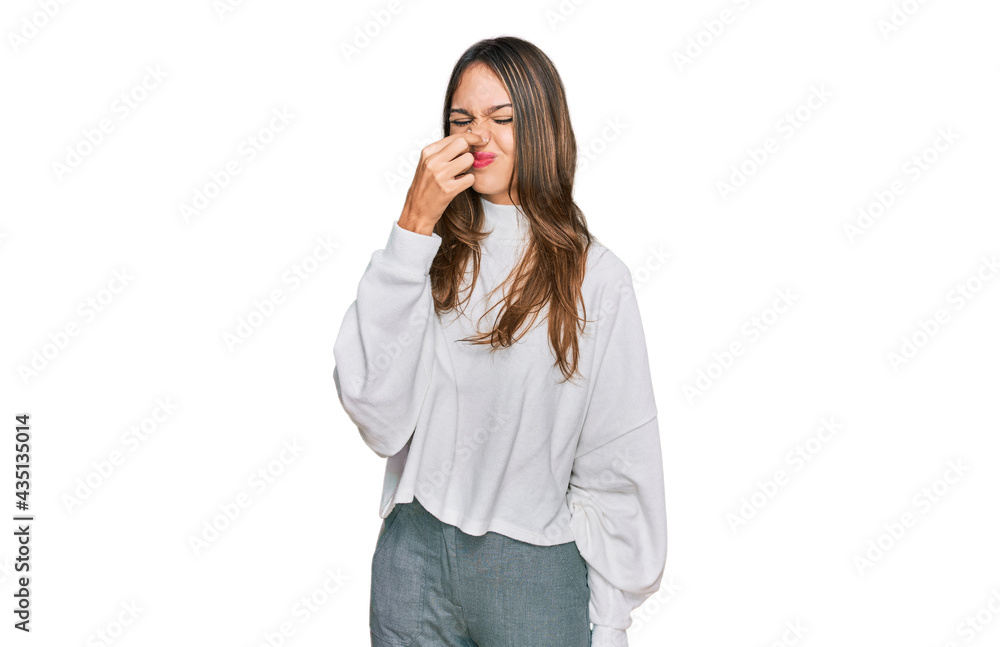 Young brunette woman wearing casual turtleneck sweater smelling something stinky and disgusting, intolerable smell, holding breath with fingers on nose. bad smell Young brunette woman wearing casual turtleneck sweater smelling something stinky and disgusting, intolerable smell, holding breath with fingers on nose. bad smell