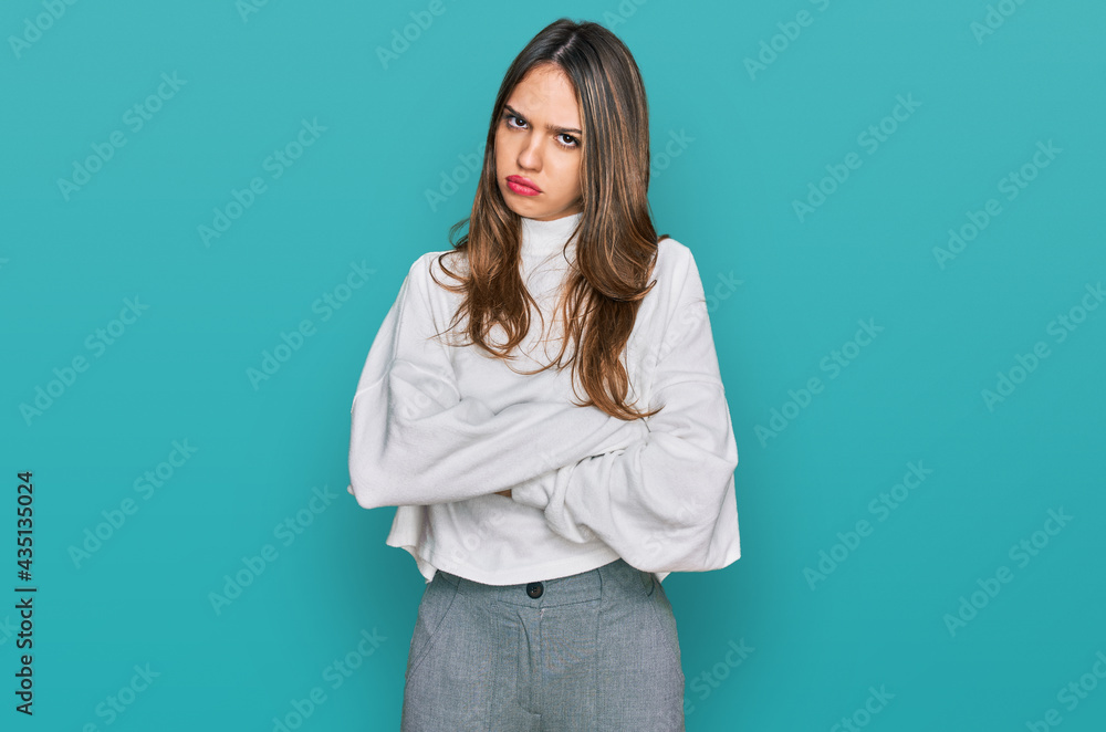 Young brunette woman wearing casual turtleneck sweater skeptic and nervous, disapproving expression on face with crossed arms. negative person. Young brunette woman wearing casual turtleneck sweater skeptic and nervous, disapproving expression on face with crossed arms. negative person.