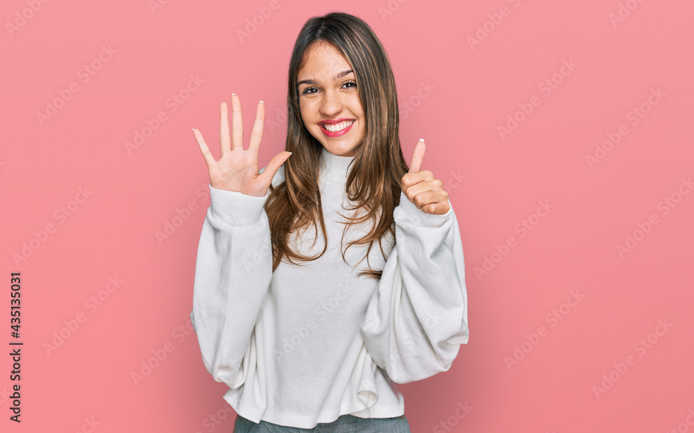 Fototapeta premium Young brunette woman wearing casual turtleneck sweater showing and pointing up with fingers number six while smiling confident and happy.