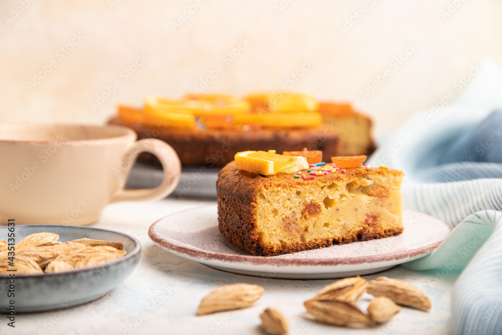 Orange cake with almonds and a cup of coffee on a white concrete background. Top view, selective focus. Orange cake with almonds and a cup of coffee on a white concrete background. Top view, selective focus.