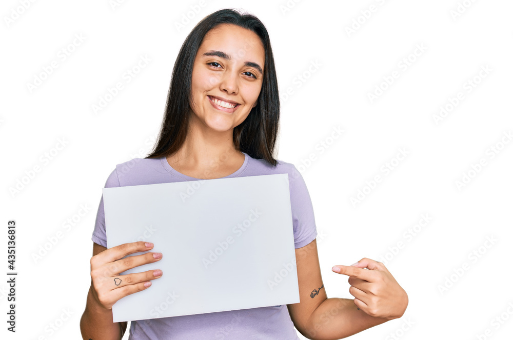 Young hispanic woman holding blank empty banner smiling happy pointing with hand and finger Young hispanic woman holding blank empty banner smiling happy pointing with hand and finger