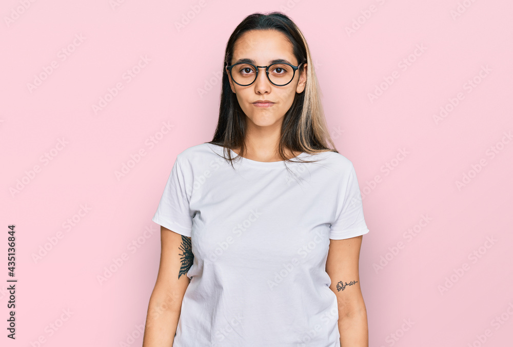 Young hispanic woman wearing casual white t shirt relaxed with serious expression on face. simple and natural looking at the camera. Young hispanic woman wearing casual white t shirt relaxed with serious expression on face. simple and natural looking at the camera.