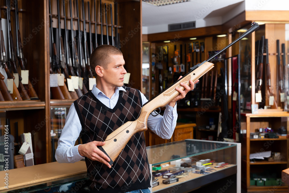 Gun shop salesman with air rifle in hand