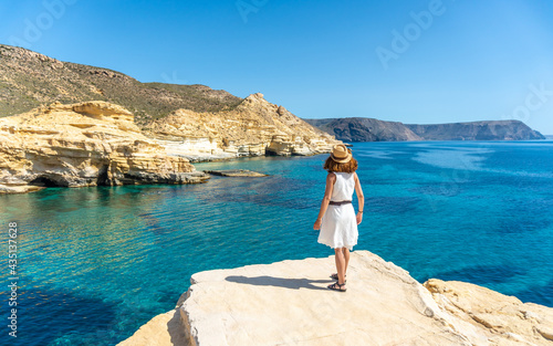 A young woman in a white dress looking at the sea in Rodalquilar in Cabo de Gata on a beautiful summer day, Almería. Mediterranean sea, spain