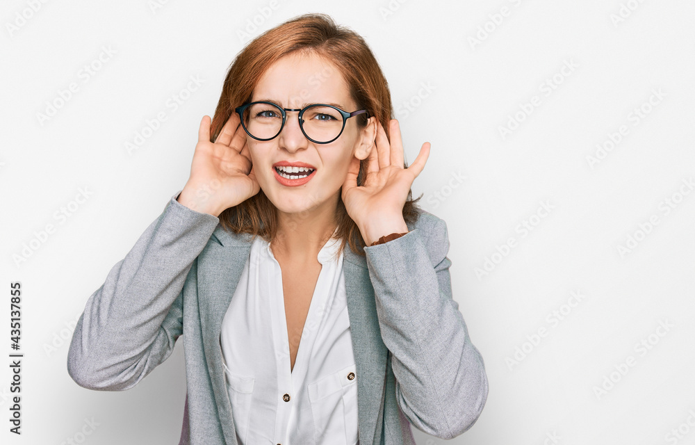 Young caucasian woman wearing business style and glasses trying to hear both hands on ear gesture, curious for gossip. hearing problem, deaf