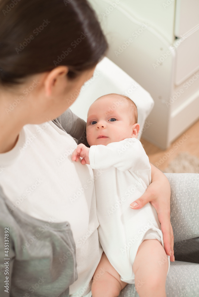 Portrait of happy mother and baby, parent and little kid relaxing at home. Family having fun together.