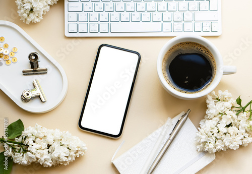 Neutral color tabletop with keyboard, lilac flowers and smartpohone mock-up with white screen isolated photo