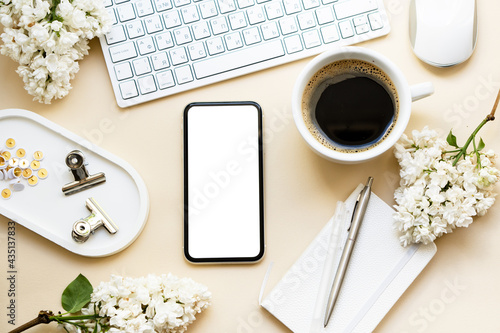 Neutral color tabletop with keyboard, lilac flowers and smartpohone mock-up with white screen isolated photo