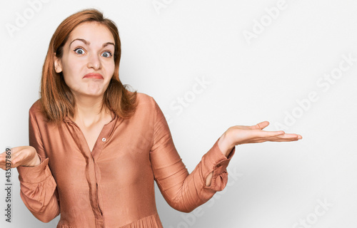 Young caucasian woman wearing sexy party dress clueless and confused expression with arms and hands raised. doubt concept.