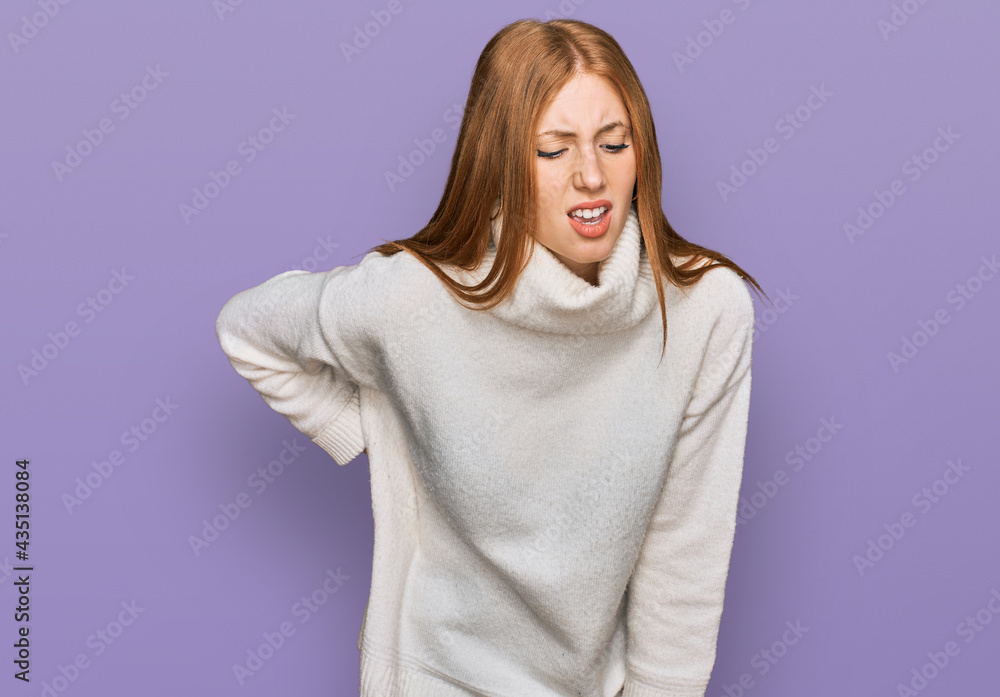 Young irish woman wearing casual winter sweater suffering of backache, touching back with hand, muscular pain Young irish woman wearing casual winter sweater suffering of backache, touching back with hand, muscular pain