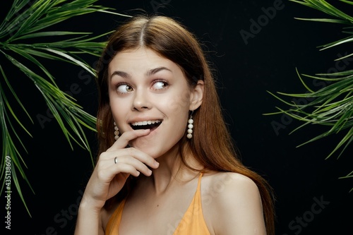 cheerful woman in a swimsuit green leaves the dark background exotic