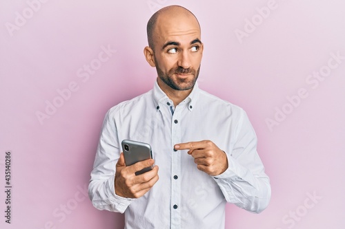 Young hispanic man using smartphone smiling looking to the side and staring away thinking. © Krakenimages.com