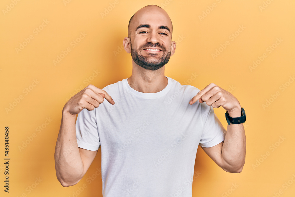 Young bald man wearing casual white t shirt looking confident with smile on face, pointing oneself with fingers proud and happy. Young bald man wearing casual white t shirt looking confident with smile on face, pointing oneself with fingers proud and happy.
