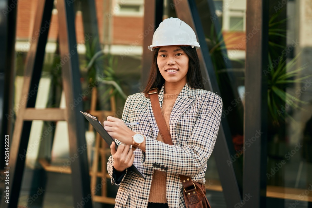 Young asian architect woman smiling happy writing on clipboard at the city. Young asian architect woman smiling happy writing on clipboard at the city.