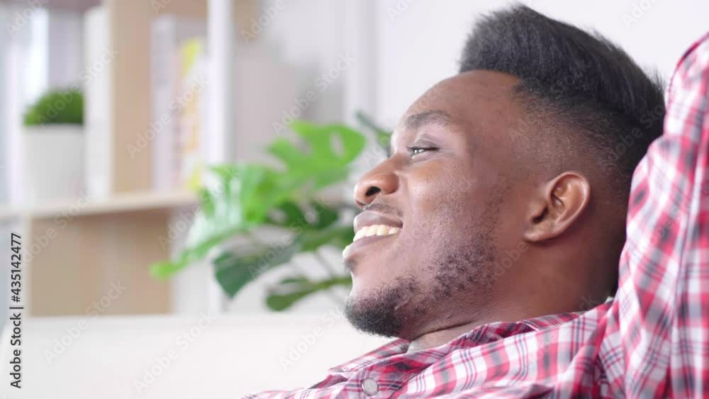 African man spending weekend to stay in living room at home sitting on sofa to watch some movies, happy holiday. Staying home and safe. Quarantine concept. Having relief face African man spending weekend to stay in living room at home sitting on sofa to watch some movies, happy holiday. Staying home and safe. Quarantine concept. Having relief face