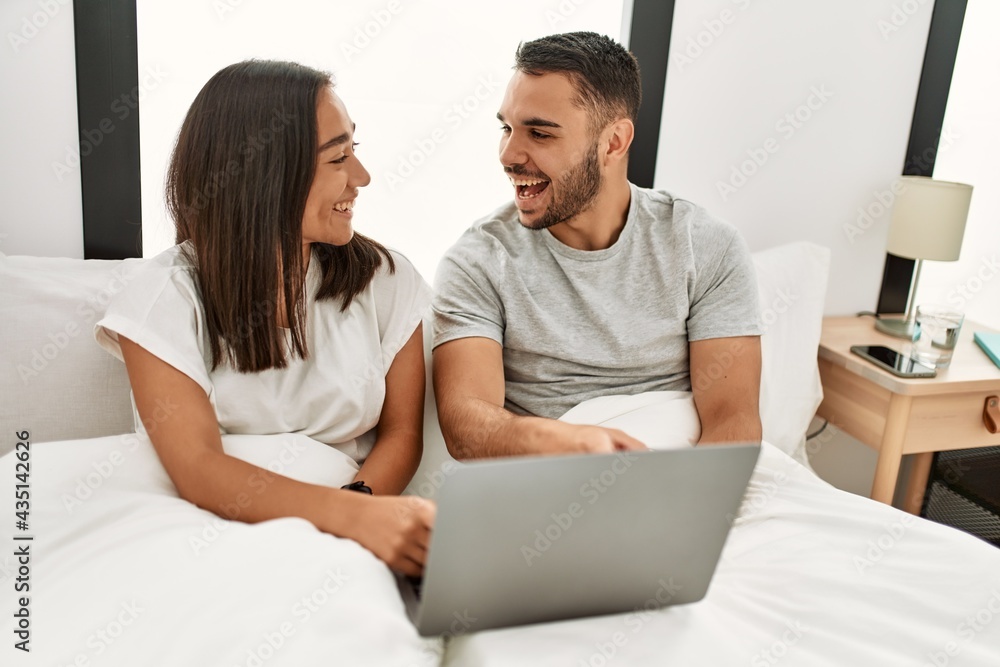 Young latin couple smiling happy using laptop at bedroom Young latin couple smiling happy using laptop at bedroom