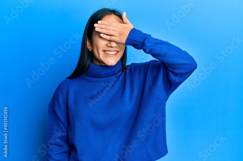Young asian woman wearing casual winter sweater smiling and laughing with hand on face covering eyes for surprise. blind concept. © Krakenimages.com