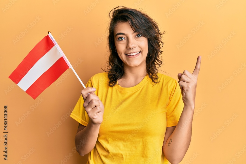 Young hispanic woman holding austria flag smiling happy pointing with hand and finger to the side Young hispanic woman holding austria flag smiling happy pointing with hand and finger to the side
