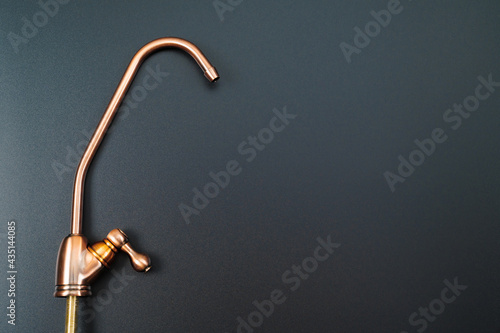 Brass tap to filter drinking water on a black background. photo