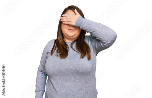 Beautiful brunette plus size woman wearing casual clothes covering eyes with hand, looking serious and sad. sightless, hiding and rejection concept