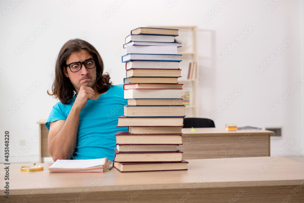 Young male student and a lot of books in the class Young male student and a lot of books in the class