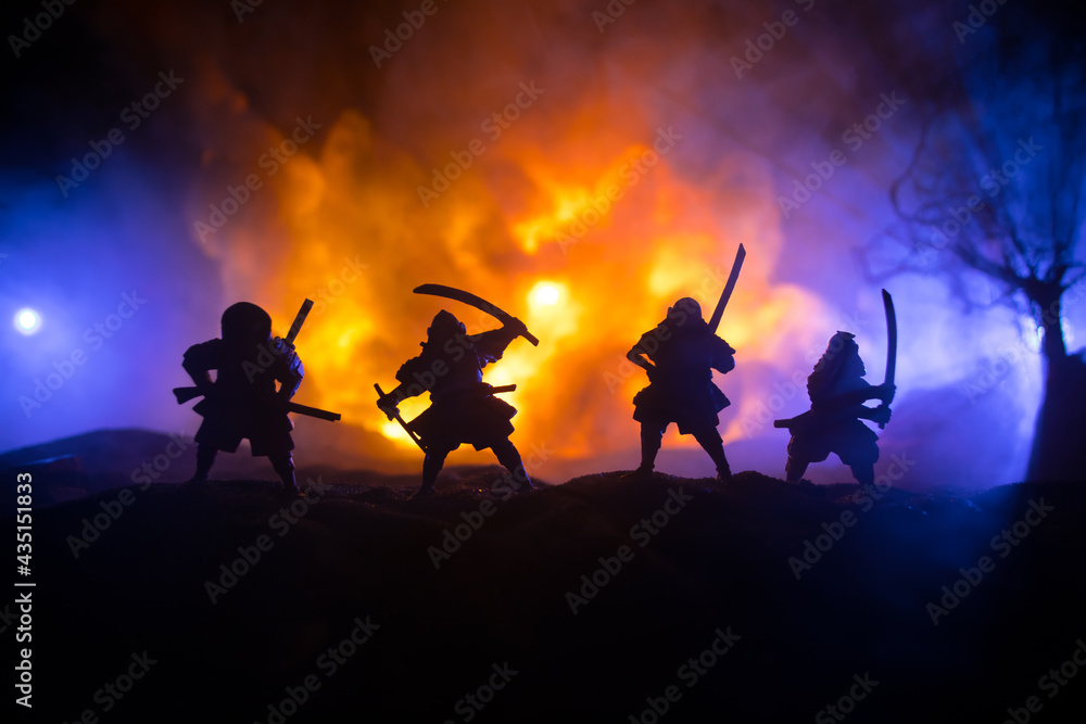 Fototapeta premium Samurai fighting concept. Silhouette of samurais in duel near tree and old temple. Table decoration with dark toned foggy background. Selective focus