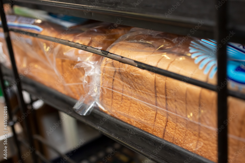 A view of several bags of sliced white bread, on a tray rack, in a restaurant kitchen setting.